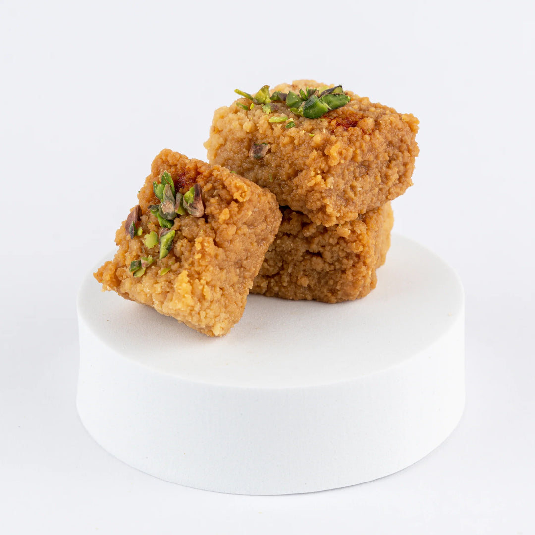 Three square pieces of Horlicks Kalakand on a white plate with a white background.