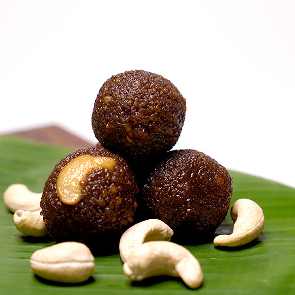 Spherical Karupatti Laddu placed on a banana leaf with visible cashew nuts around.