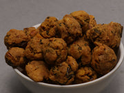 A bowl of freshly made Cashew Pakoda, which are crispy golden-brown morsels, served on a white plate.