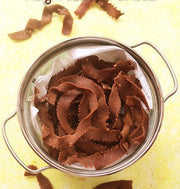 A bowl filled with ragi ootu pakoda, which are crispy millet crackers, on a yellow background with a few crackers scattered outside the bowl.