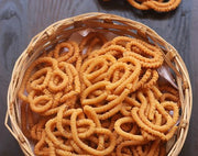A basket filled with golden brown Thinai Murukku snack.