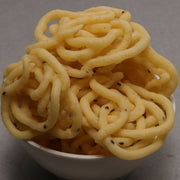 A bowl of Ulundu Muruku, which are puffed rice snacks, displayed on a white surface.