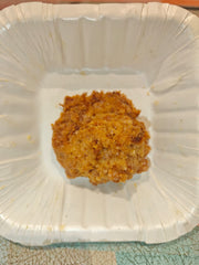 A single coconut biscuit on a white plate with a crumbly texture.