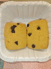 Two vanilla chocolate chip cookies placed on a white paper plate.