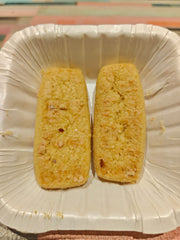 Two Badam Stick Cookies placed on a white disposable plate.