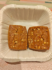 Two cashew nut cookies on a disposable plate with a white border.