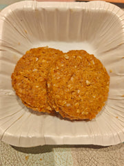 Two round oats biscuits on a white paper plate.