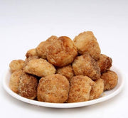 A plate of golden-brown fried snack items, possibly mini doughnuts or fritters, on a white background.