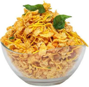 A glass bowl filled with corn mixture snack, which includes corn flakes and string cheese, garnished with green leaves.